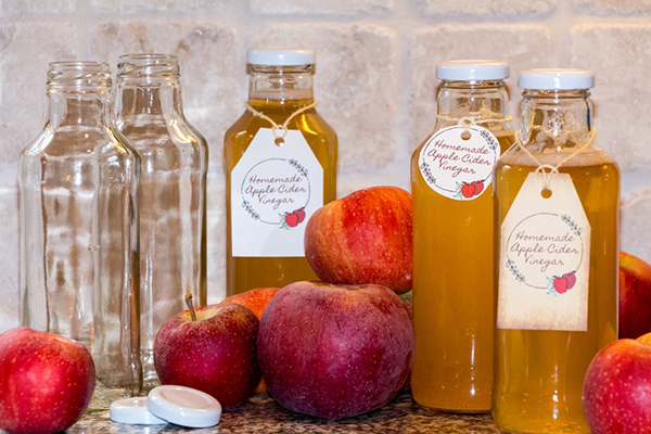 Amber-colored apple cider vinegar in a clear glass bottle, set against a light background.
