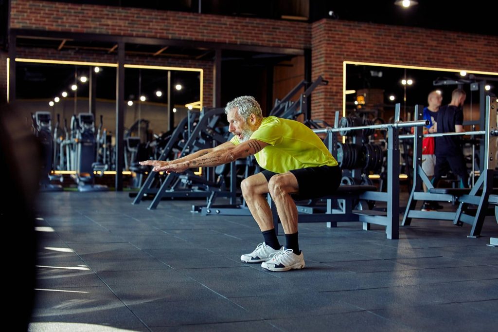 senior man bodyweight squat gym
